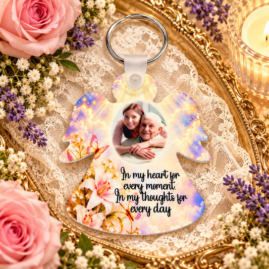 Personalised memorial angel photo keyring displayed on lace with pink roses, purple flowers and candle
