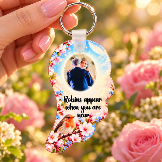 Robin memorial angel wing photo keyring held in hand against a soft pink rose background