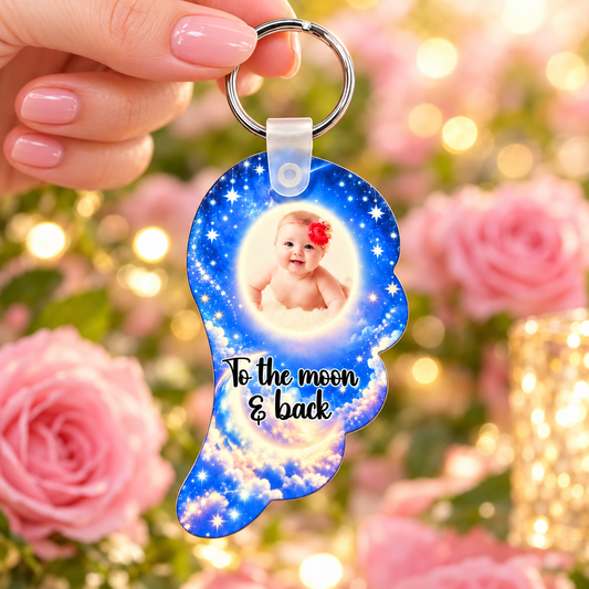 Blue starry sky baby memorial angel wing photo keyring held against soft pink roses