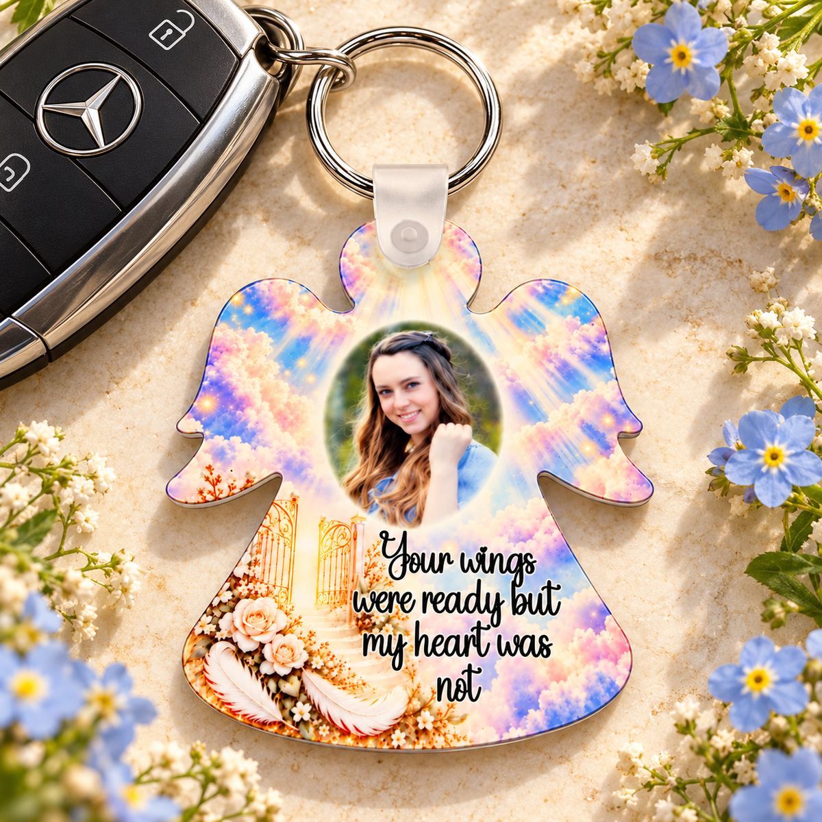Heaven's Gates memorial angel acrylic keyring beside car keys and blue flowers, personalised with a photograph and sympathy verse