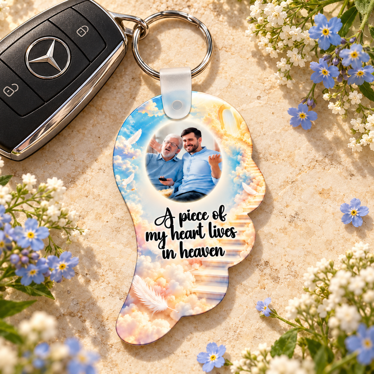 Personalised heavenly angel wing memorial photo keyring beside Mercedes car keys and blue flowers