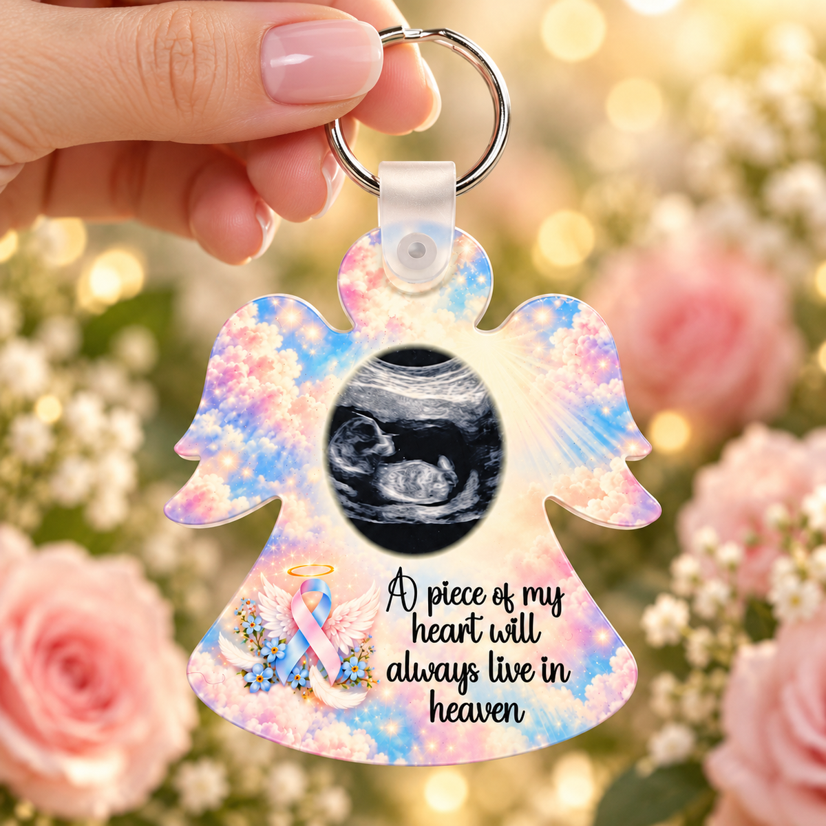 Baby loss memorial angel scan photo keyring held in hand against a soft pink rose background