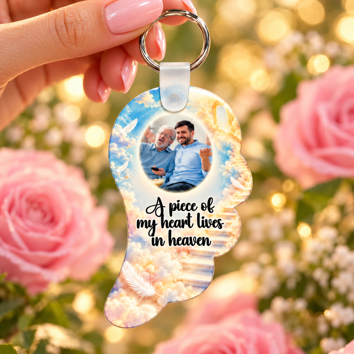 A Piece of My Heart Lives in Heaven angel wing photo keyring held against a soft pink floral background