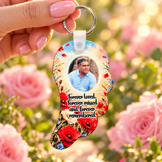 Poppy memorial angel wing photo keyring held in hand against a soft pink floral background
