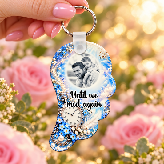 Blue memorial angel wing photo keyring held in hand against a soft pink rose background
