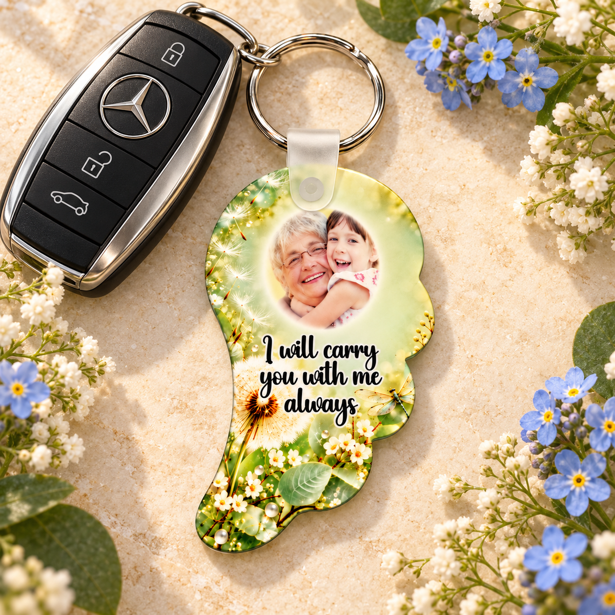 Personalised dandelion memorial angel wing keyring beside Mercedes car keys and blue flowers