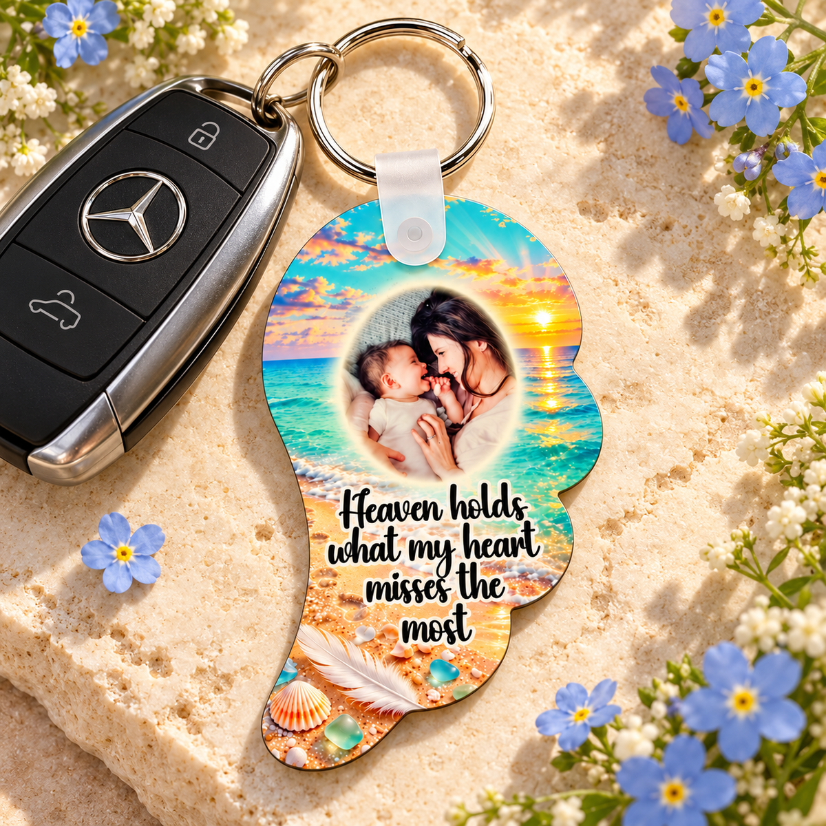 Personalised angel wing remembrance keyring beside Mercedes car keys and blue flowers