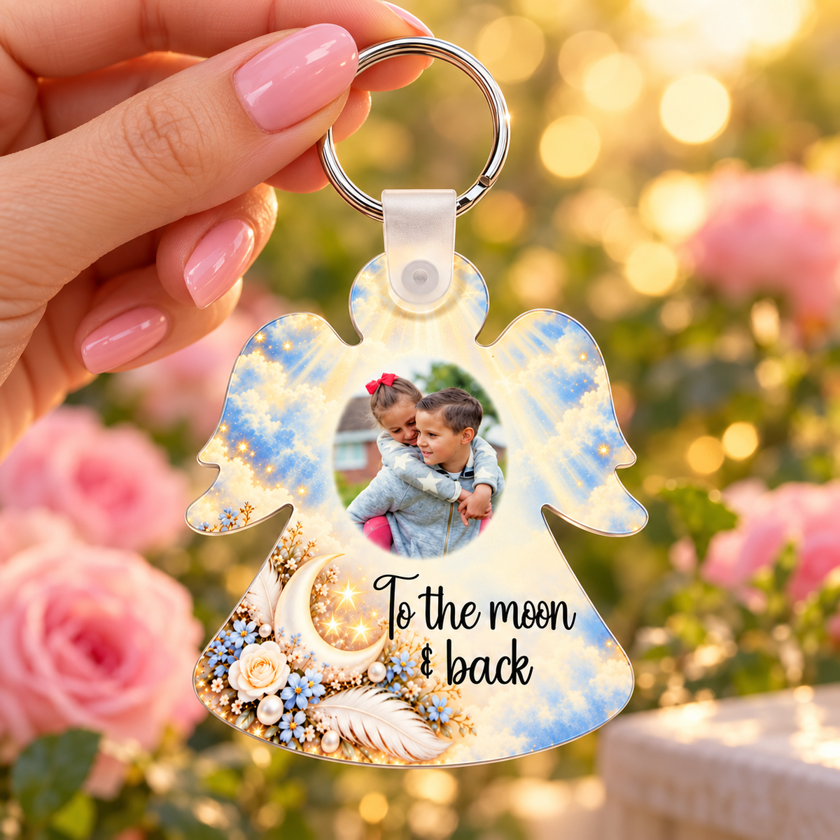 To the Moon and Back personalised angel photo keyring held in hand against soft pink roses and warm fairy lights